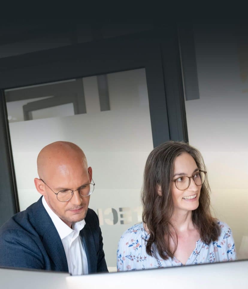 Beratende schauen im Büro gemeinsam auf einen Monitor und besprechen die Ergebnisse