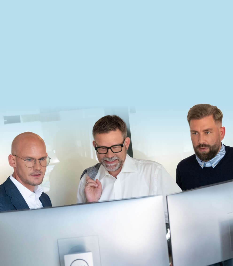 Drei Beratende schauen gemeinsam auf zwei Monitore und stimmen ein Zielbild ab