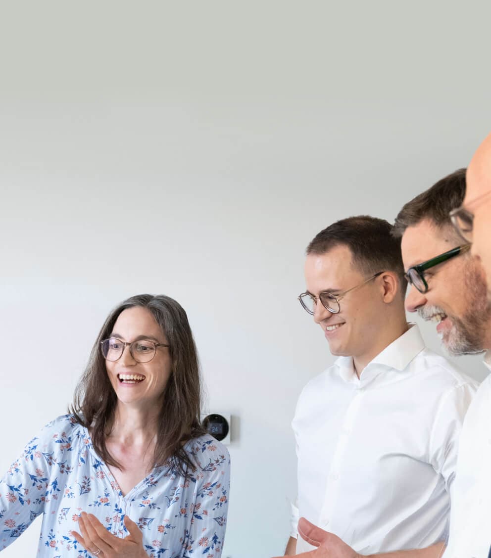 Beraterin erklärt lachend drei Kollegen einen Sachverhalt