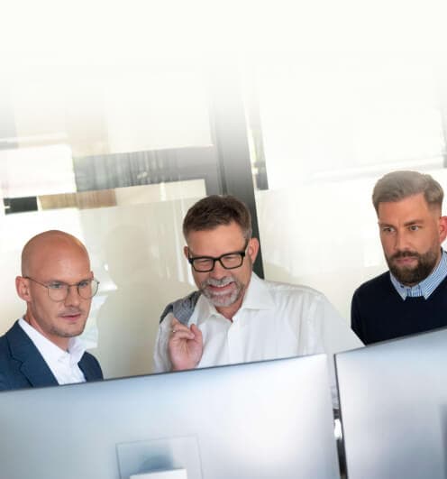 Drei Berater testen gemeinsam Anwendungen an zwei Monitoren