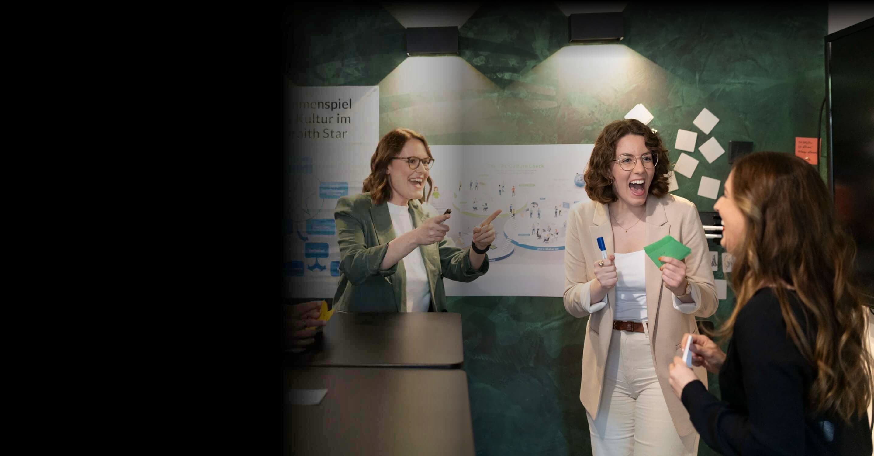 Drei Beraterinnen lachen im Workshop vor Postern zum Galbraith Star und zum CPC Culture Check