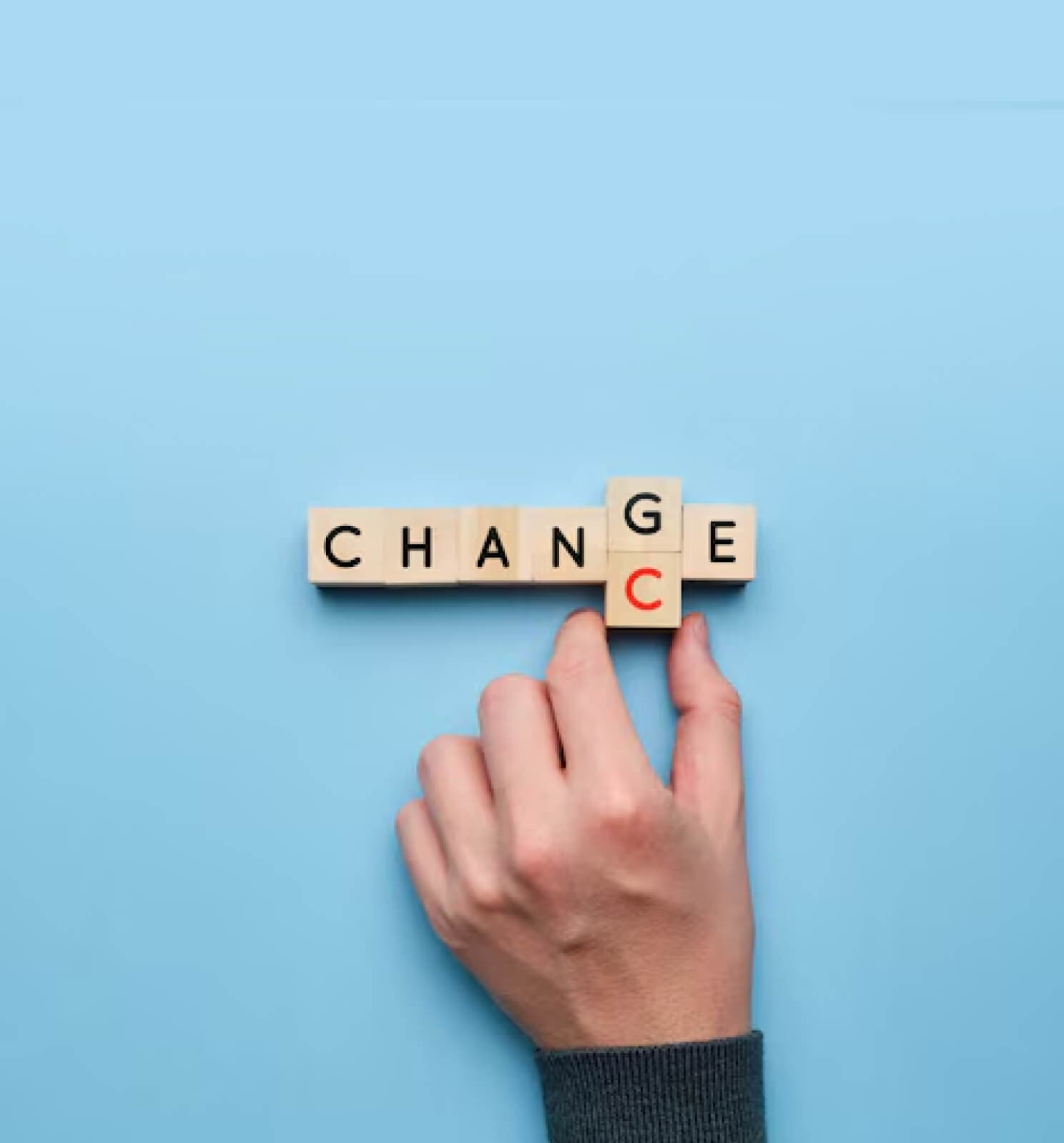 Hand setzt Buchstabenwürfel zum Wort Change zusammen