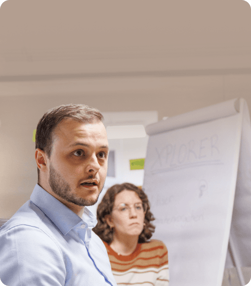 Zwei Teilnehmende eines Workshops vor einem Flipchart