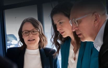 Drei Personen im konzentrierten Gespräch an einem Besprechungstisch
